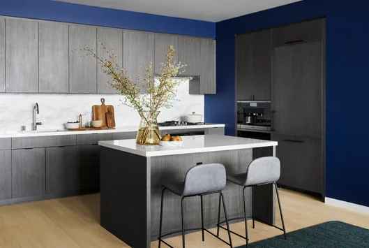 Open kitchens with custom grey-oak cabinetry, Bosch appliances, white Caesarstone counters and a Calacatta Caldia marble slab backsplash.