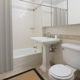 Classic marble bathrooms feature Kohler fixtures and storage-friendly oversized medicine cabinets. 
