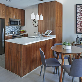 Aspire to culinary greatness in The Emerson's open kitchen with breakfast bar, featuring professional stainless steel appliances from Fisher & Paykel and Bosch, set against walnut cabinetry with Caesarstone counters and a full-height, tiled backsplash.