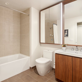 Luxurious bathrooms feature a walnut vanity, white quartz counters, and a mirrored medicine cabinet with integrated lighting