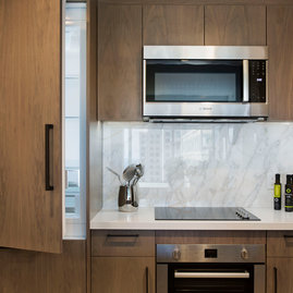 White quartz counters and Calacutta marble backsplash, soft-close wood cabinetry, stainless steel sink and premium stainless steel appliances with integrated wood paneling.