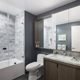 Luxe bathrooms include grey-oak vanities with marble counters, custom medicine cabinets and marble tub surround.