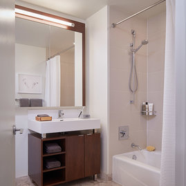 Custom bathrooms with polished natural stone floors, custom walnut vanities, and oversized showers.