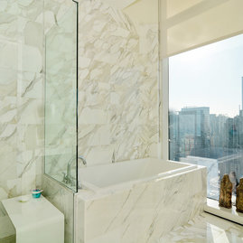 Custom bathrooms with polished natural stone floors, custom walnut vanities, and oversized showers