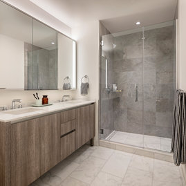 Well-appointed master bathrooms feature double vanities with Italian white marble, grey marble walls, and medicine cabinets with integrated lighting and pulls.