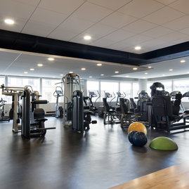 A state-of-the art Health and Fitness Center features cardio and strength equipment and lots of natural light streaming through a wall of windows.