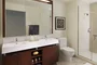 Custom bathrooms with polished natural stone floors, custom walnut vanities, and oversized showers