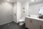 Luxe baths include a custom grey oak bathroom vanity with marble counters, frameless glass-enclosed showers with marble tile wet walls and oversized porcelain tile flooring.
