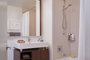 Custom bathrooms with polished natural stone floors, custom walnut vanities, and oversized showers.