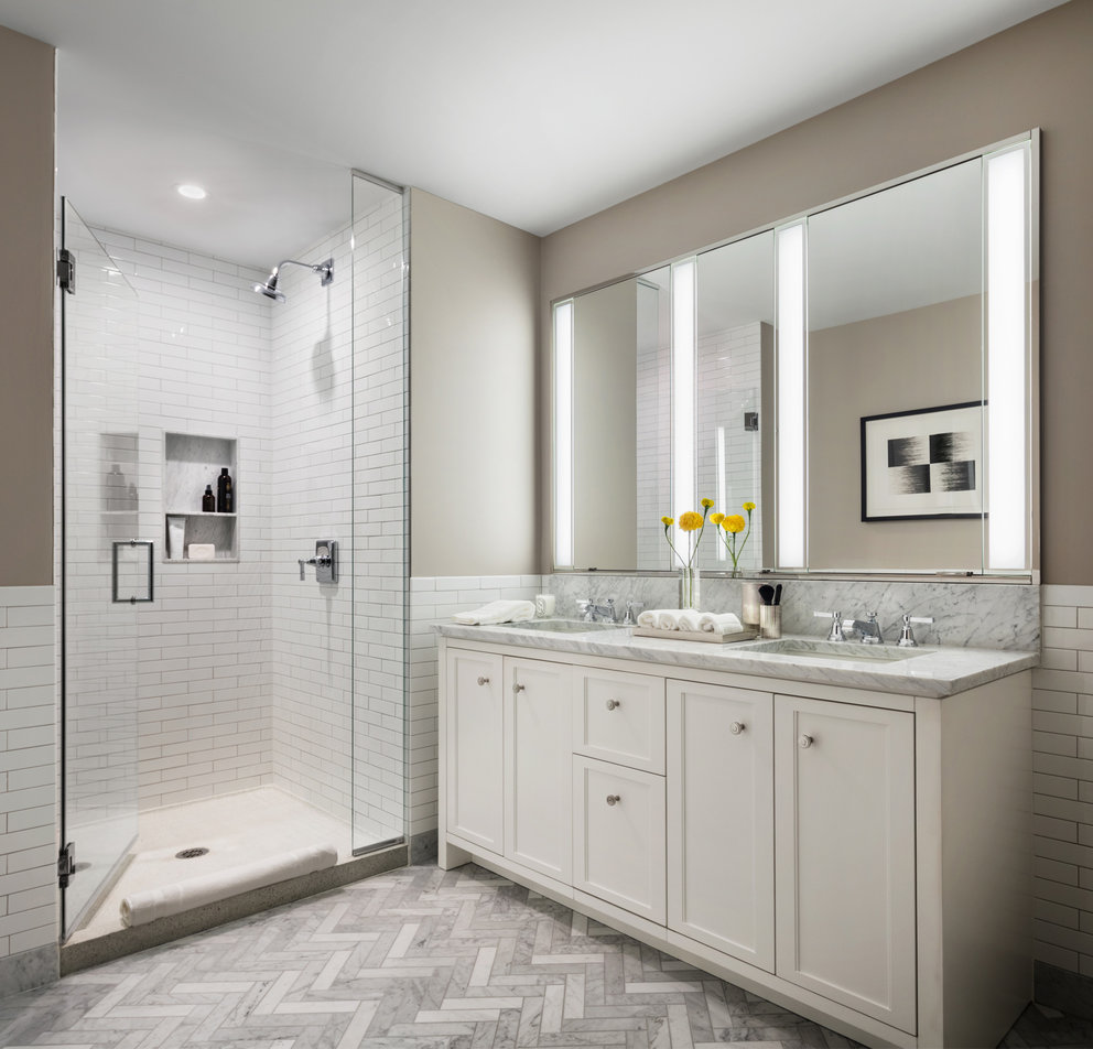 Master baths featuring white natural stone vanities, Kohler fixtures, and natural stone tile floors.