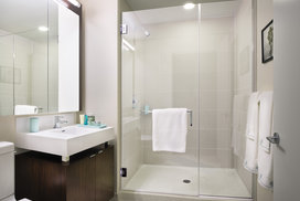 Custom bathrooms with polished natural stone floors, custom walnut vanities, and oversized showers