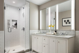 Luxuriate in master baths featuring white natural stone vanity, Kohler fixtures and accessories in polished chrome, and natural stone tile floor in white herringbone tile.