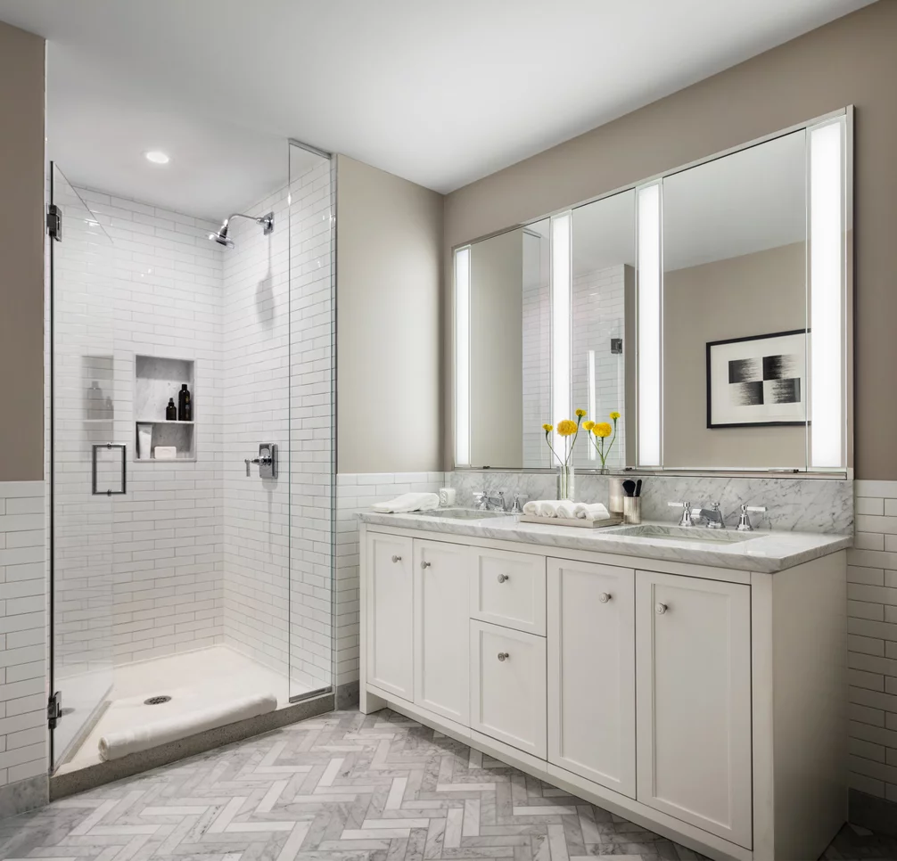 Master baths featuring white natural stone vanities, Kohler fixtures, and natural stone tile floors.