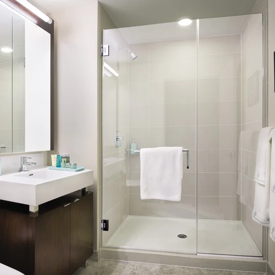 Custom bathrooms with polished natural stone floors, custom walnut vanities, and oversized showers