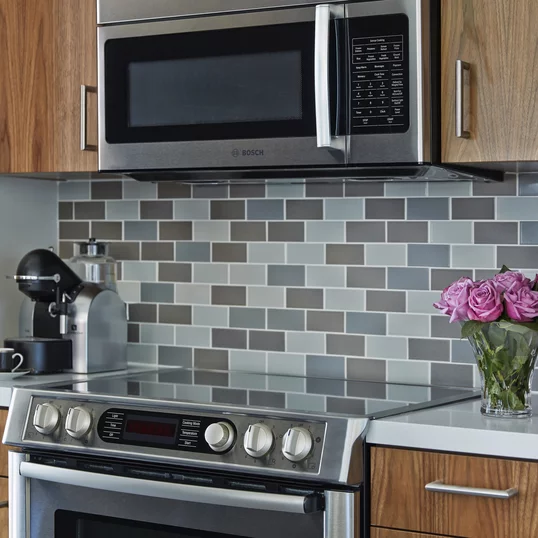 Aspire to culinary greatness in The Emerson's open kitchen with breakfast bar, featuring professional stainless steel appliances from Fisher & Paykel and Bosch, set against walnut cabinetry with Caesarstone counters and a full-height, tiled backsplash.