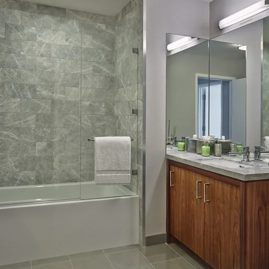 The lavish baths in The Emerson's apartments feature a marble counter and tub surround, walnut vanity with a Toto undermount sink, chrome fixtures and a mirrored medicine cabinet for additional storage.