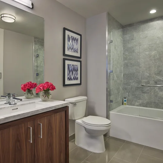 The lavish baths in The Emerson's apartments feature a marble counter and tub surround, walnut vanity with a Toto undermount sink, chrome fixtures and a mirrored medicine cabinet for additional storage.