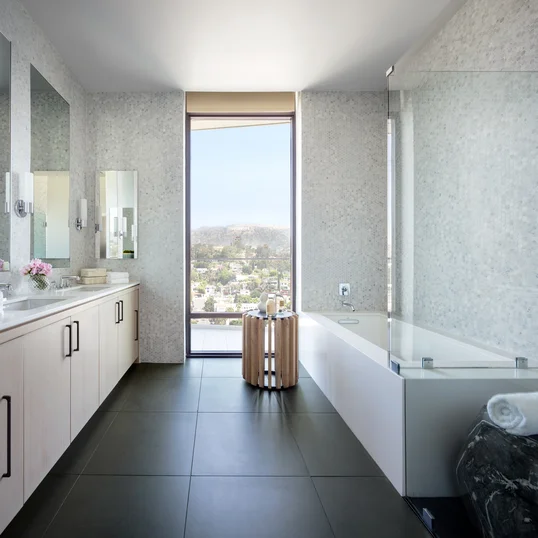Luxe baths include a custom grey oak bathroom vanity with marble counters, frameless glass-enclosed showers with marble tile wet walls and oversized porcelain tile flooring.