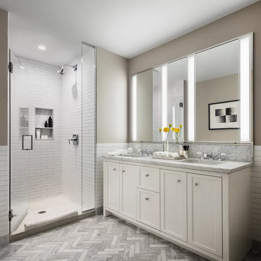 Luxuriate in master baths featuring white natural stone vanity, Kohler fixtures and accessories in polished chrome, and natural stone tile floor in white herringbone tile.