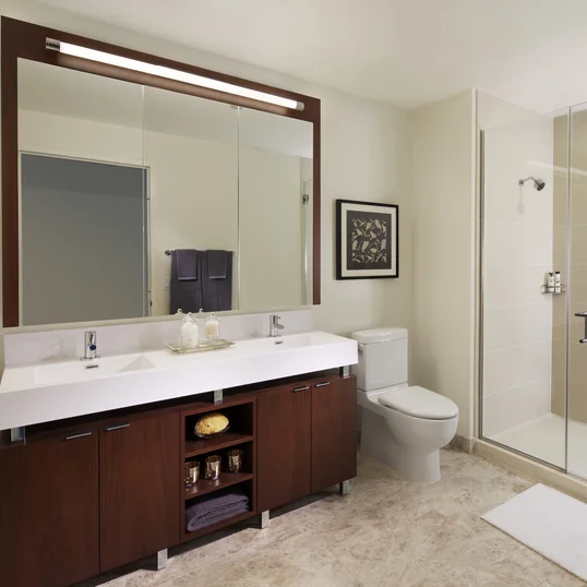 Custom bathrooms with polished natural stone floors, custom walnut vanities, and oversized showers