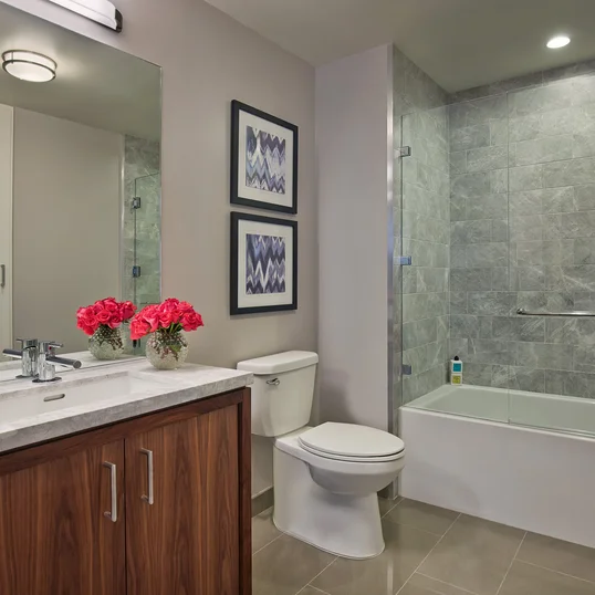 The lavish baths in The Emerson's apartments feature a marble counter and tub surround, walnut vanity with a Toto undermount sink, chrome fixtures and a mirrored medicine cabinet for additional storage.