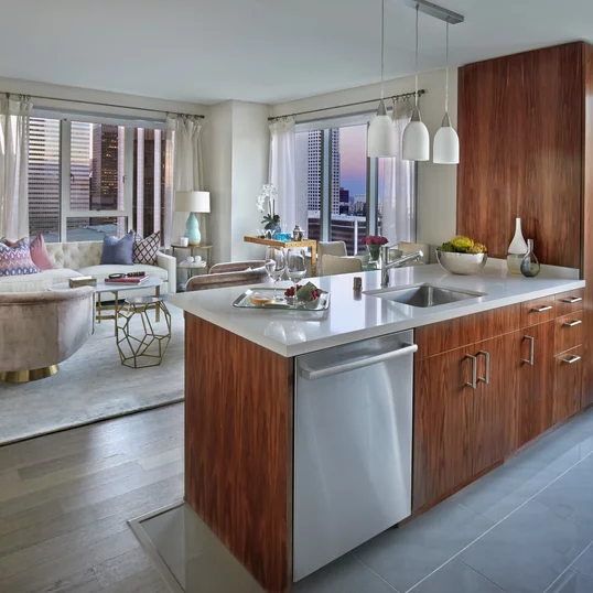 Aspire to culinary greatness in The Emerson's open kitchen with breakfast bar, featuring professional stainless steel appliances from Fisher & Paykel and Bosch, set against walnut cabinetry with Caesarstone counters and a full-height, tiled backsplash.