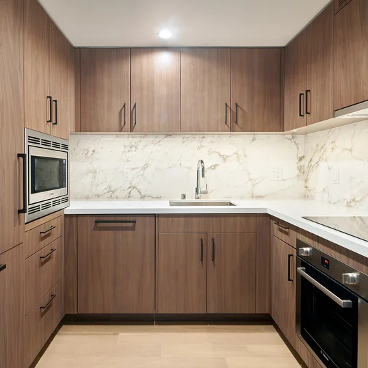 White quartz counters and Calacutta marble backsplash, soft-close wood cabinetry, stainless steel sink and premium stainless steel appliances with integrated wood paneling.