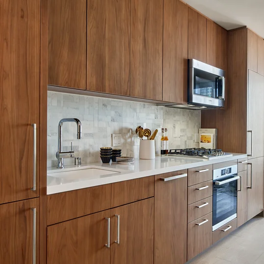 White quartz kitchen counter with a full-height Carrara marble tile backsplash