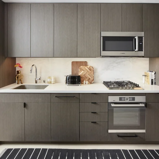 Open kitchens with custom grey-oak cabinetry, Bosch appliances, white Caesarstone counters and a Calacatta Caldia marble slab backsplash.
